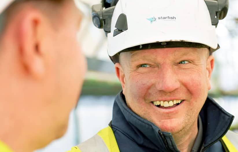 building showing scaffolding and green netting surrounded by trees