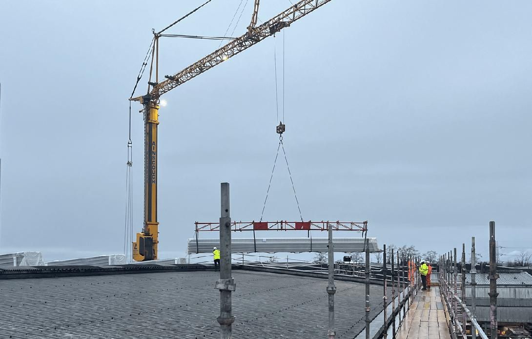 Crane positioning steel onto a industrial roof